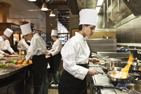 A chef and students at a cookery class in a commercial kitchen